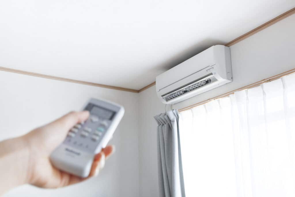 Hand with remote control directed on air conditioner